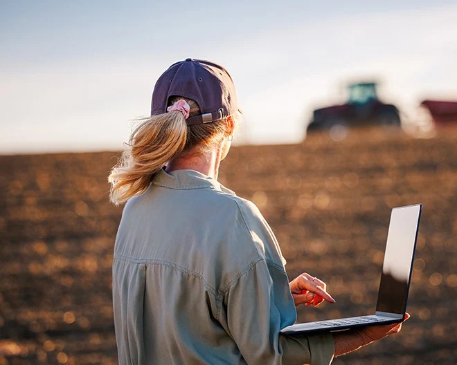 female farmer working on laptop in crops