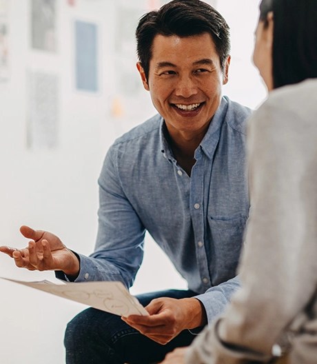 Smiling MBA candidate explaining a strategy document to a colleague during an informal leadership coaching session.
