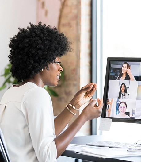 Professional woman leads an online meeting, speaking to multiple faces on a video-call grid.