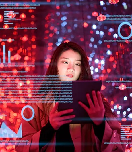 Woman holding a tablet is surrounded by vivid red-blue lights and semi-transparent charts, graphs and data streams floating in mid-air.