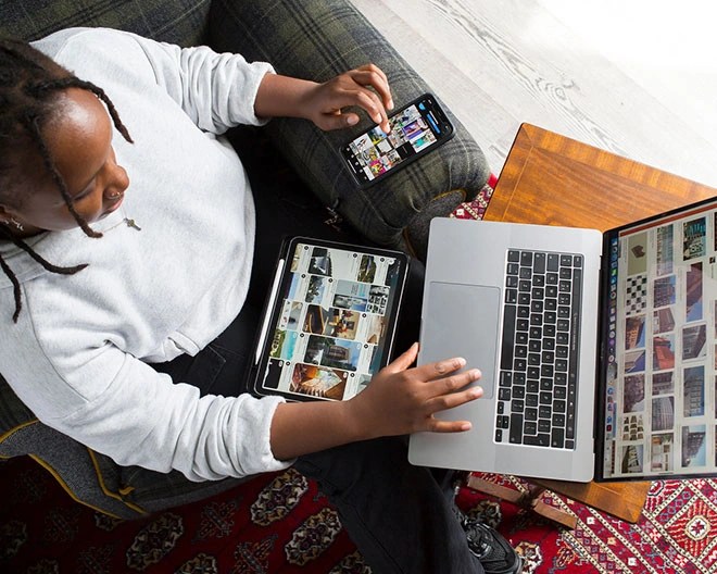 Bird’s-eye view of a design student reviewing design inspiration across a laptop, phone, and tablet.