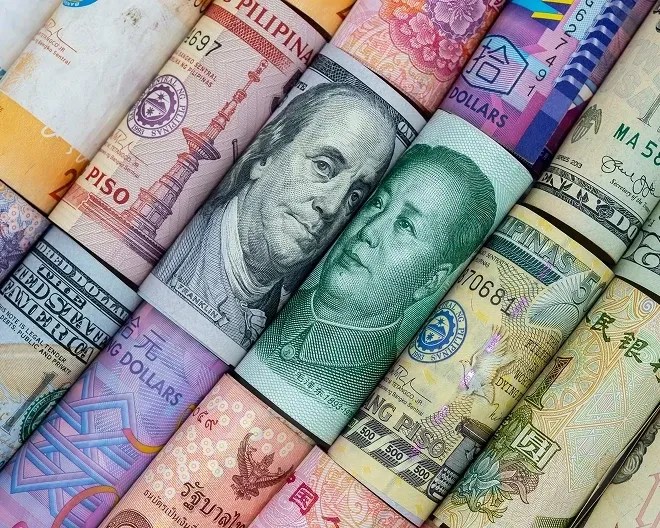 Close-up of tightly rolled, brightly coloured currency bills arranged side by side, showcasing a vibrant mix of denominations and intricate patterns.