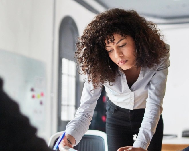 woman in an office leaning over a desk looking at documents