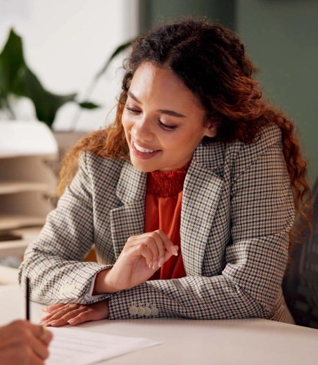 smiling woman sat at a desk looking at documents