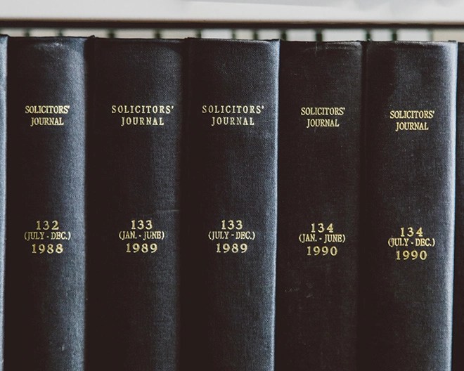 Five black hardcover volumes of the “Solicitors’ Journal” arranged vertically on a shelf, each labeled with volume number and date range in gold lettering.
