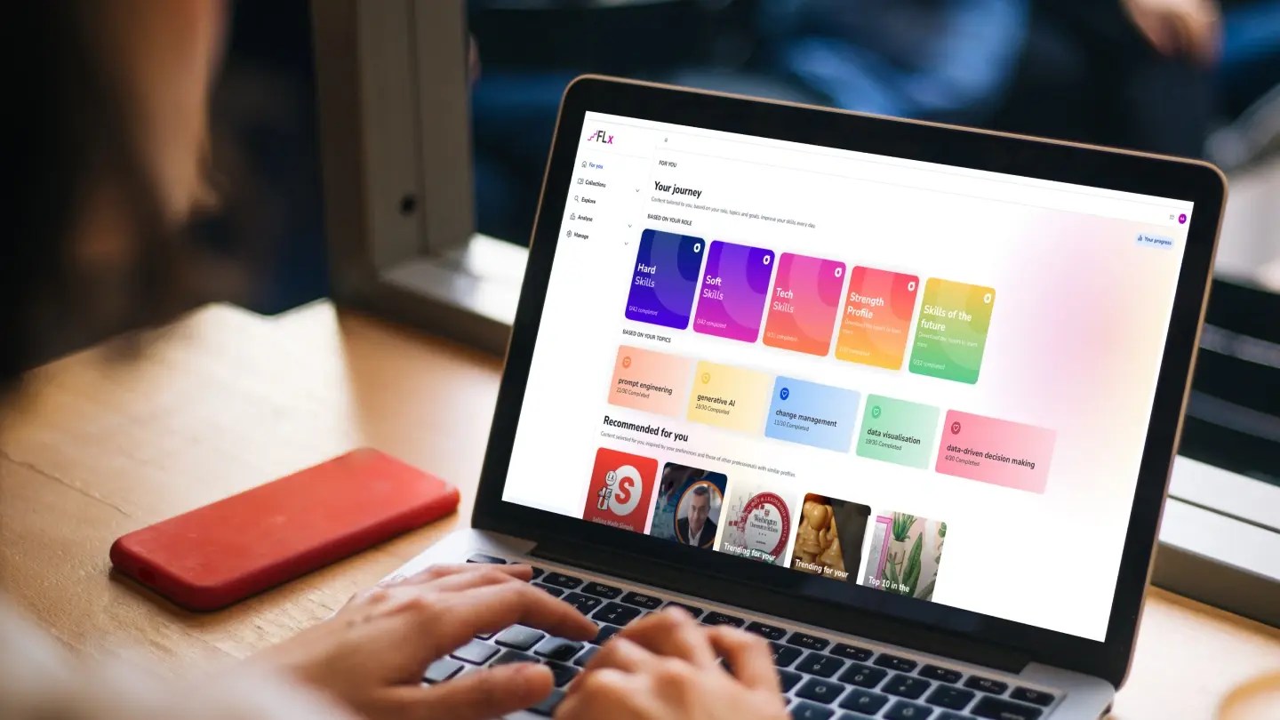 Close-up of a person’s hands typing on a laptop on a table, with a FLx user dashboard displayed on the screen.