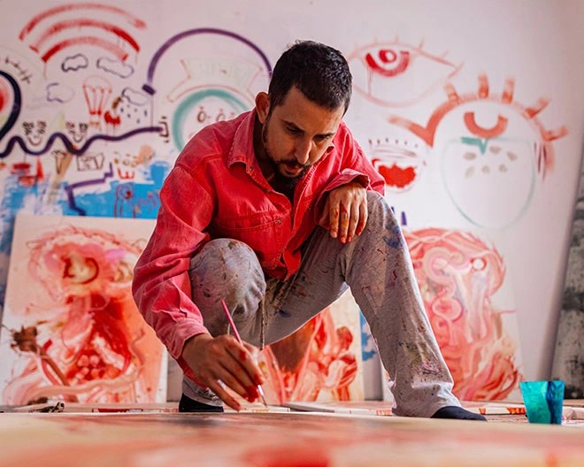 Man painting on the floor with paintings behind