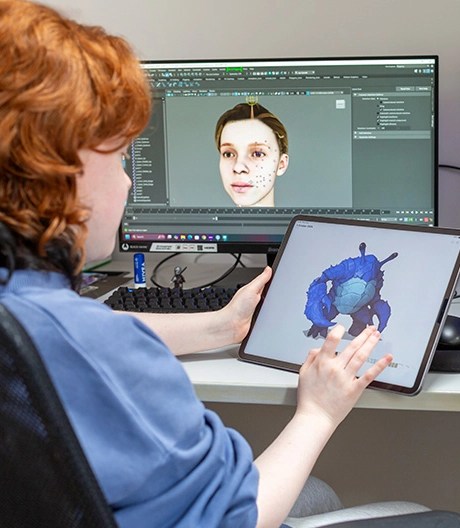 Student working on ipad and computer facing screen